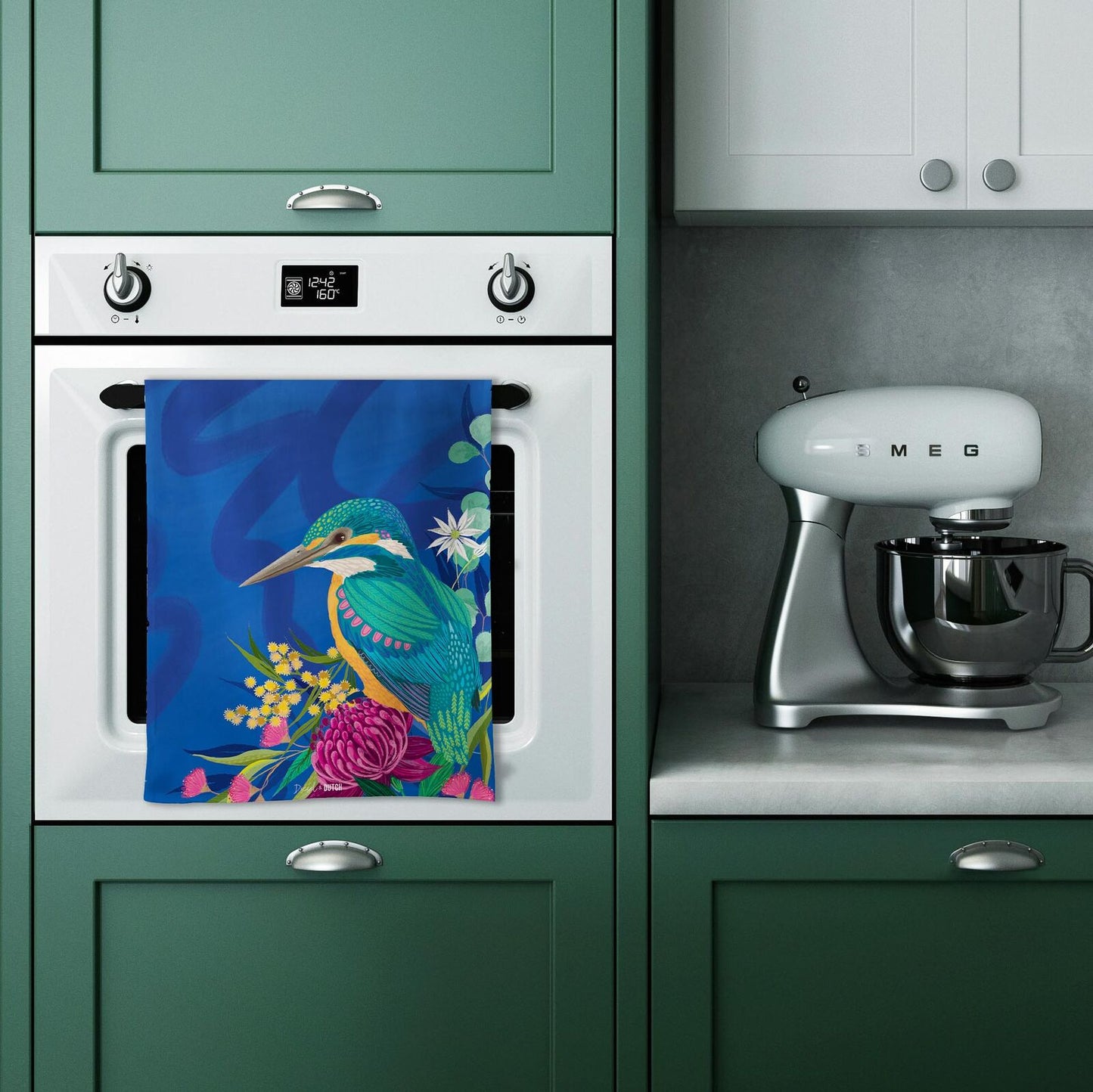 Kitchen with green cabinets, white oven, and Smeg mixer, featuring a colorful towel on the oven door.
