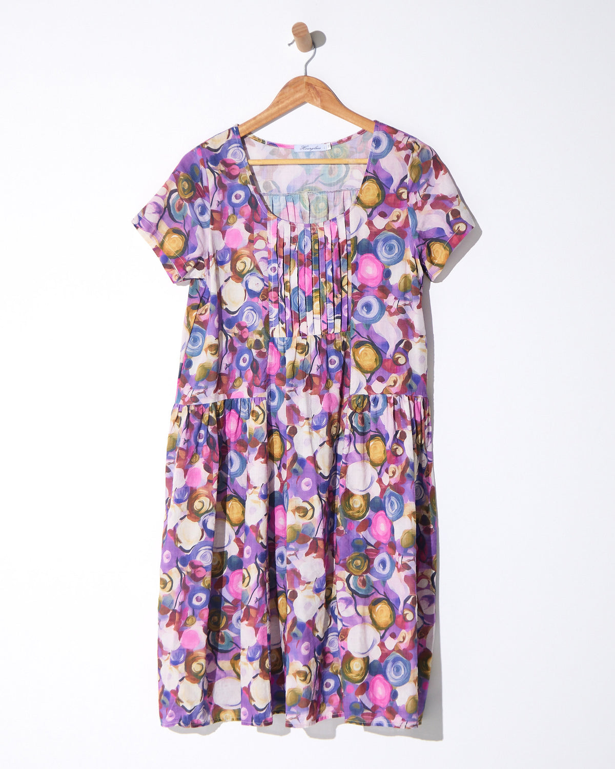 Emery Pintuck Dress in berry pop, on a hanger showing the pintuck bodice