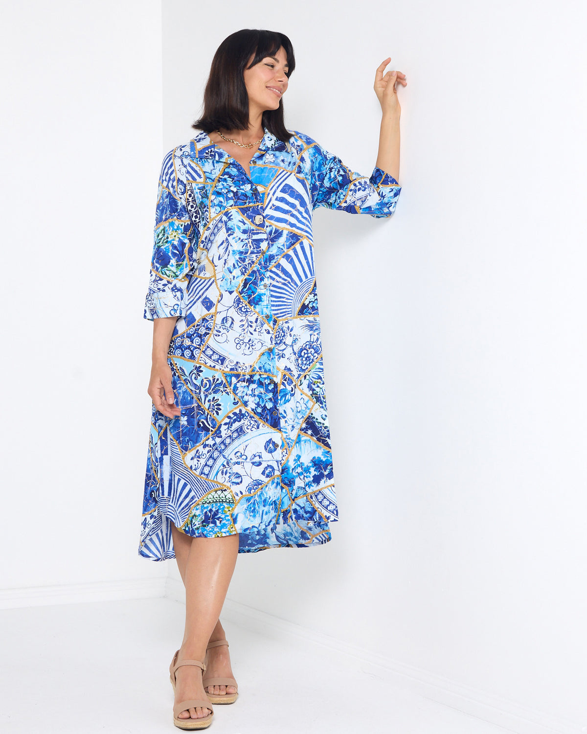 Mia Shirt Dress in patchwork print, front view leaning on a wall with arm raised