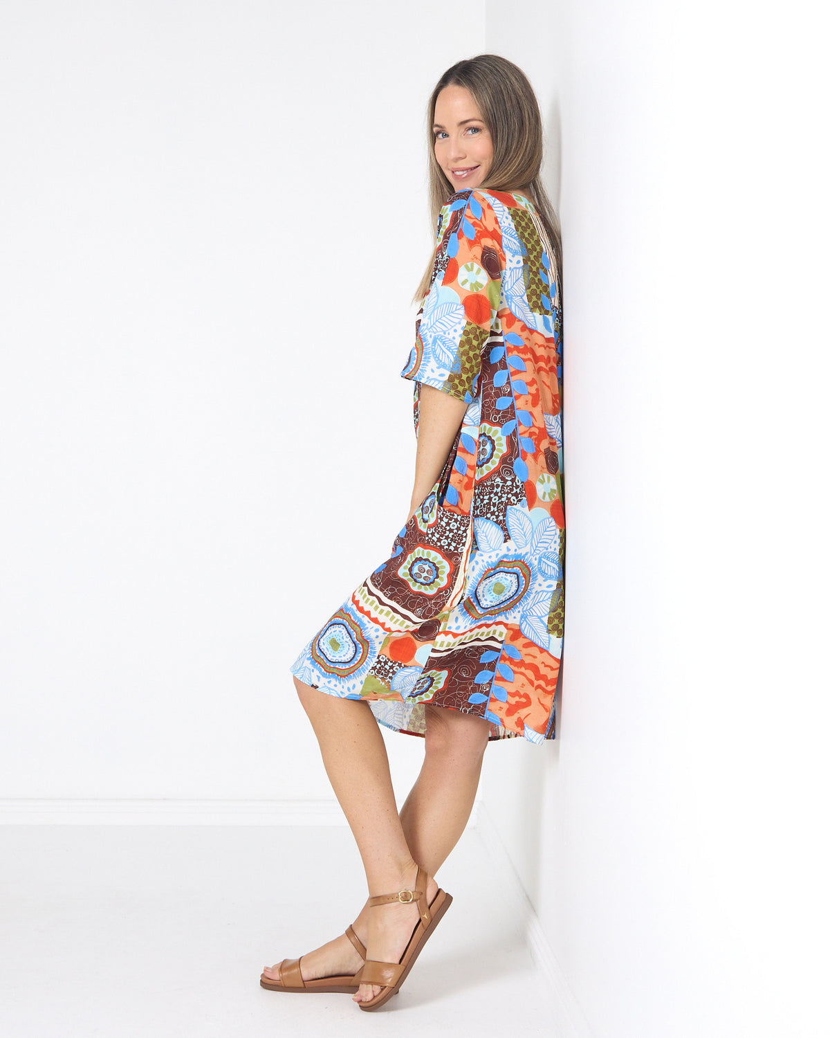 Eva Cotton Dress in ripple abstract print, side view leaning on a wall