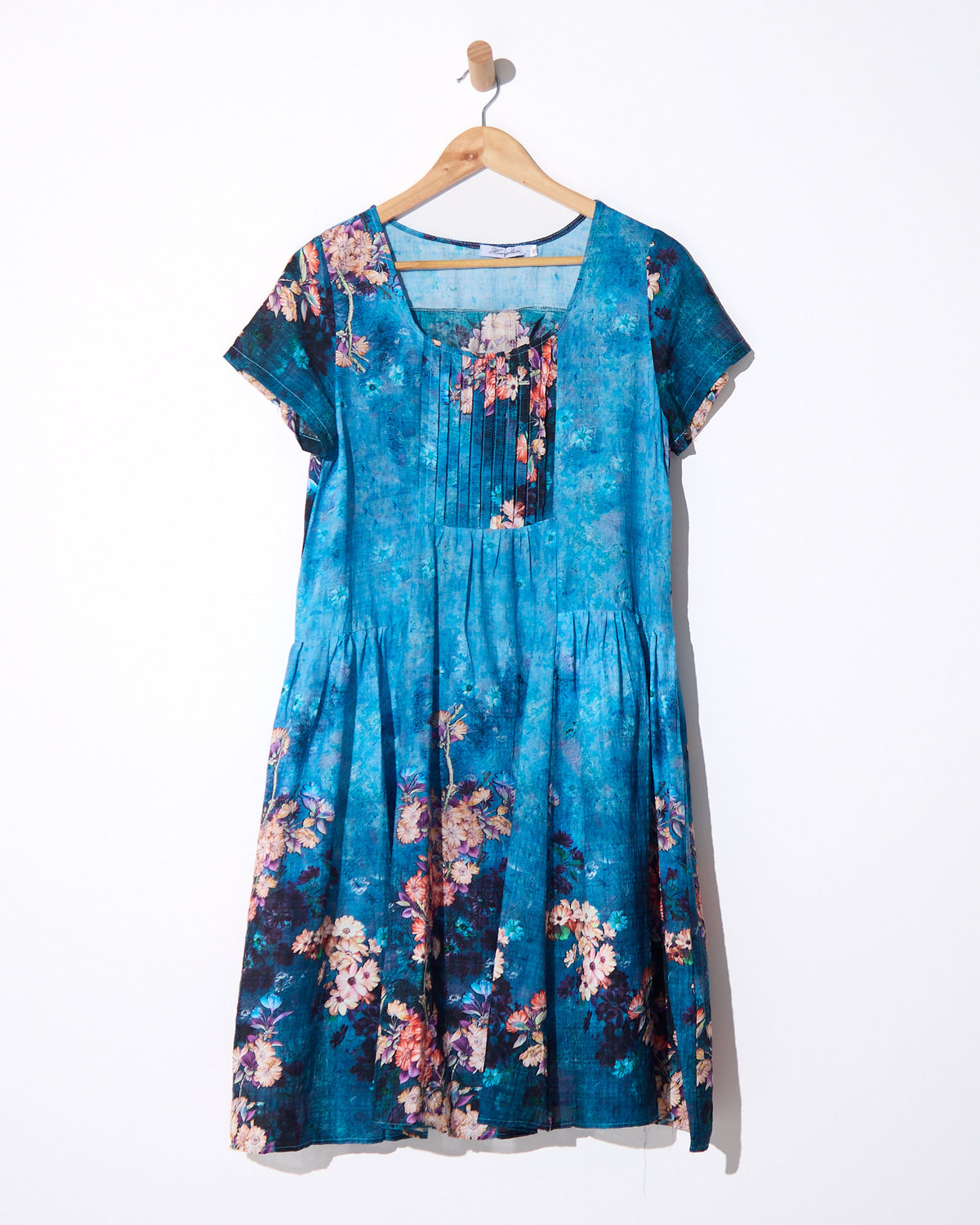 Emery Pintuck Dress in blue lagoon, on a hanger showing the pintuck bodice and print