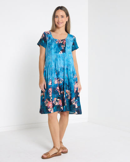 Emery Pintuck Dress in blue lagoon, full-length front view with short sleeves and floral border print
