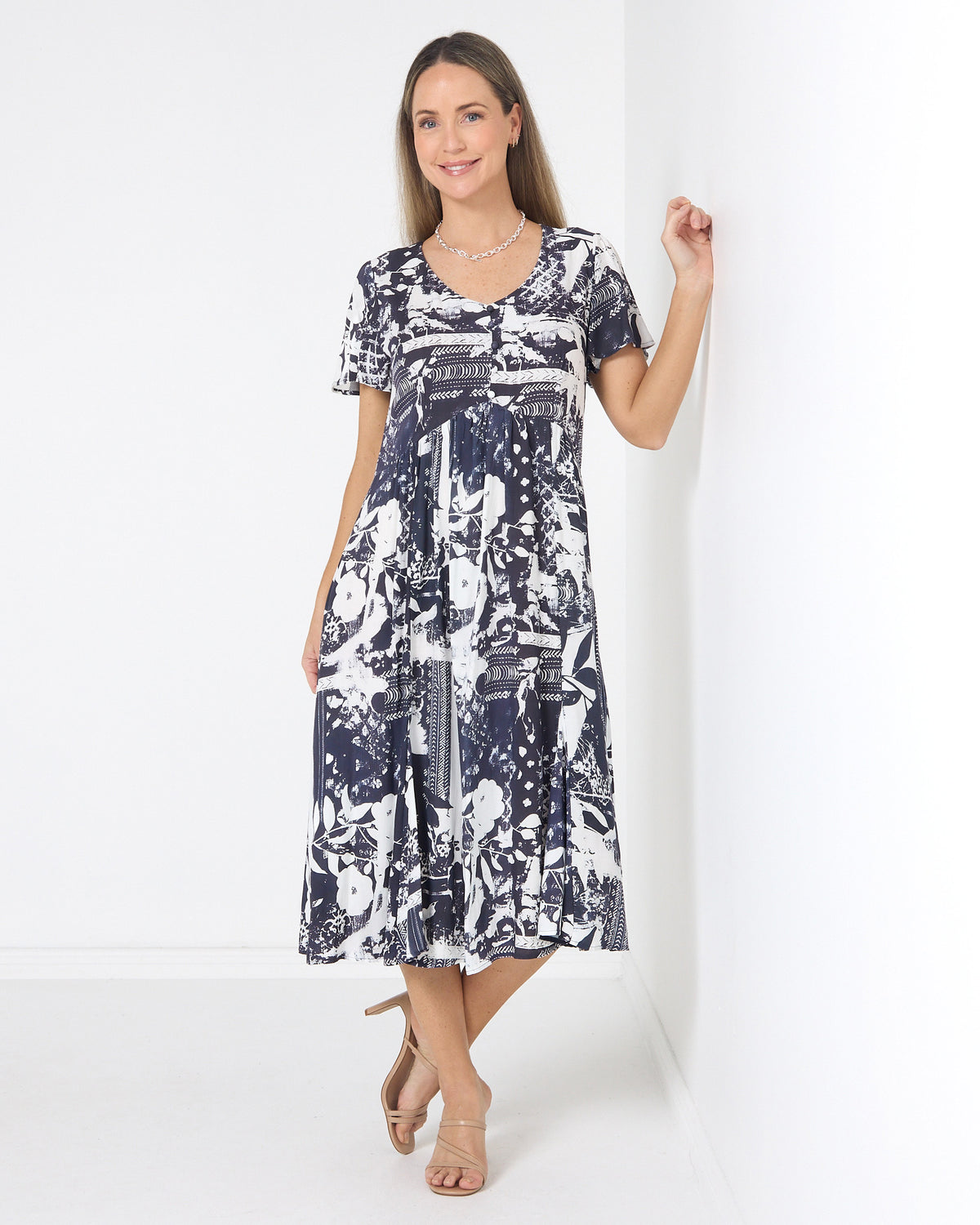 Cornwall Button Midi Dress in ink floral, front view leaning on a wall, showing the button front