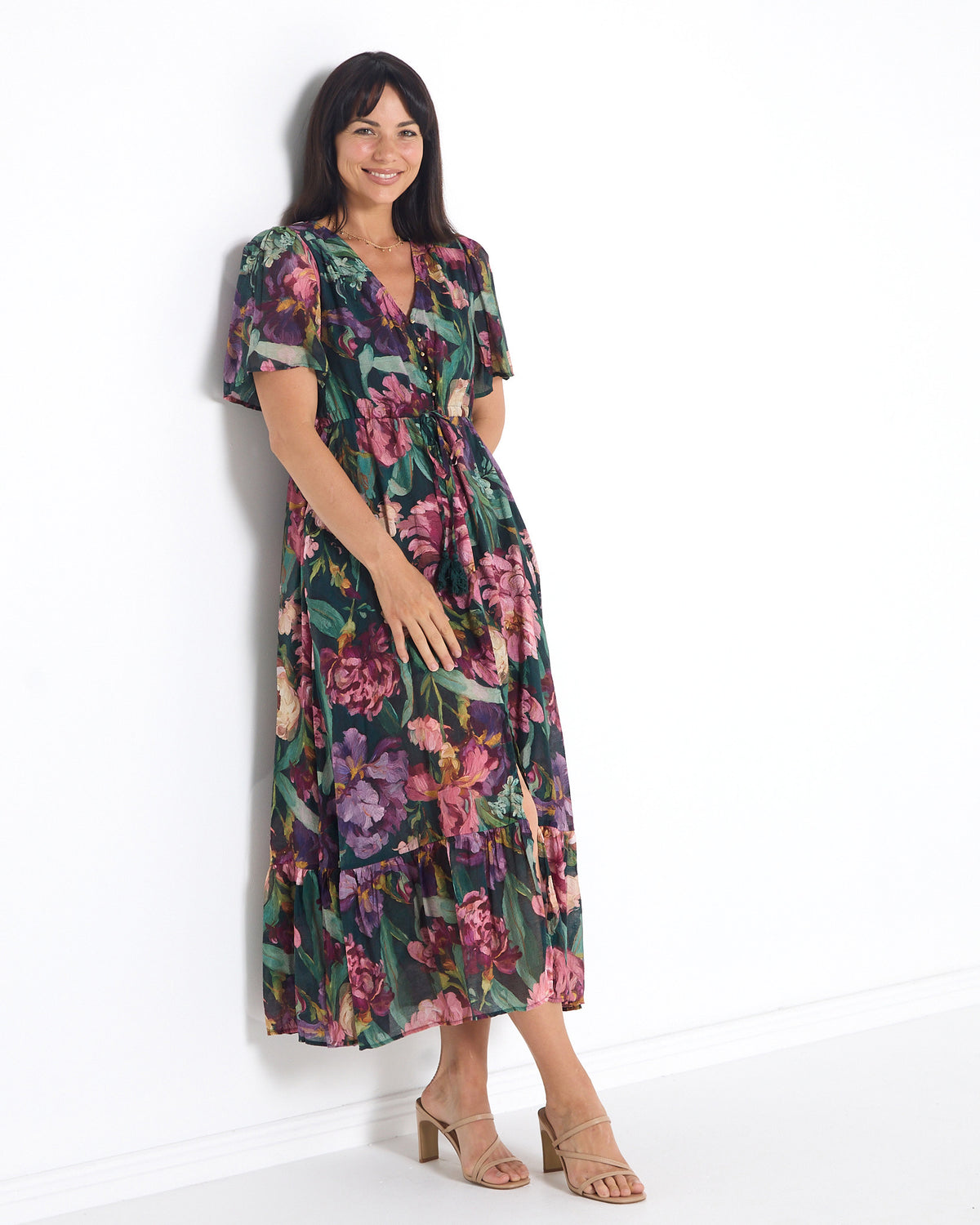 Cresida Party Dress in emerald floral, three-quarter view leaning on a wall