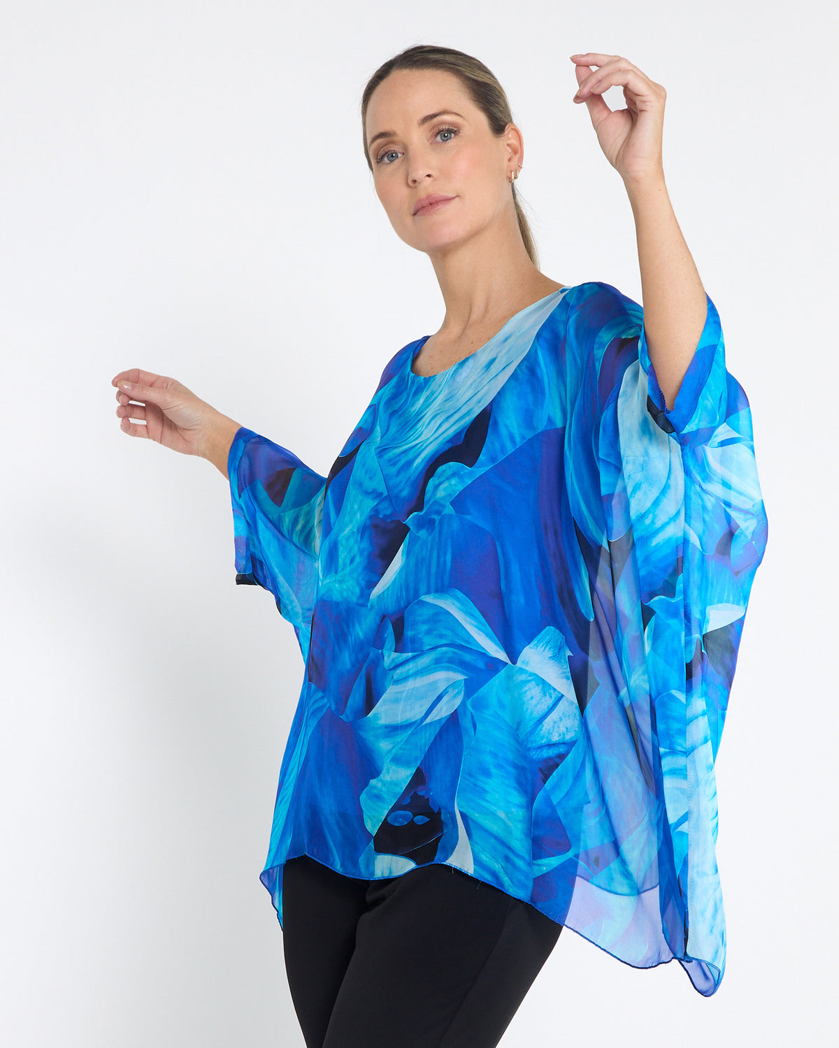 Palermo Silk Top in blue floral, front view with arms raised showing the draped sleeves