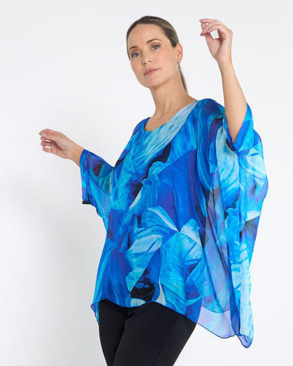 Palermo Silk Top in blue floral, front view with arms raised showing the draped sleeves
