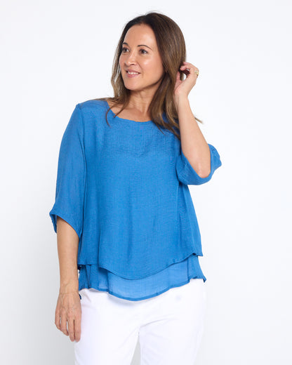 Leo Layered Top in denim blue, three-quarter front view worn with white pants