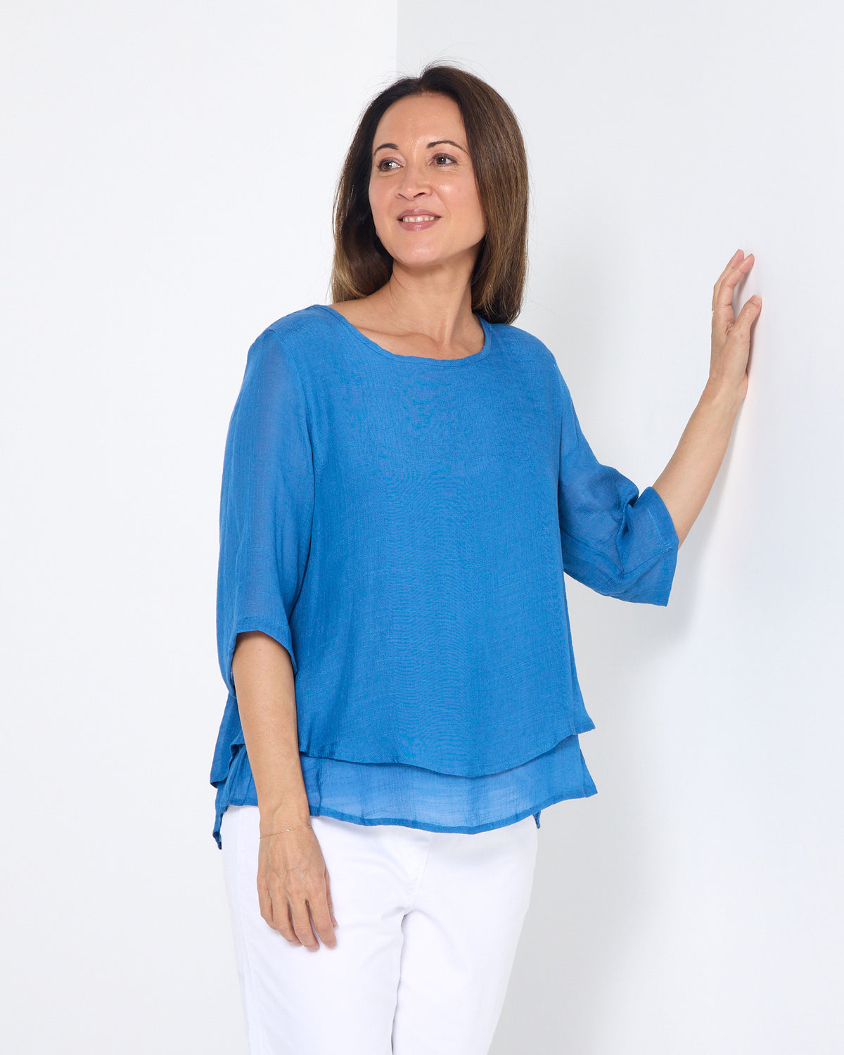 Leo Layered Top in denim blue, front view with white pants, showing the layered hem