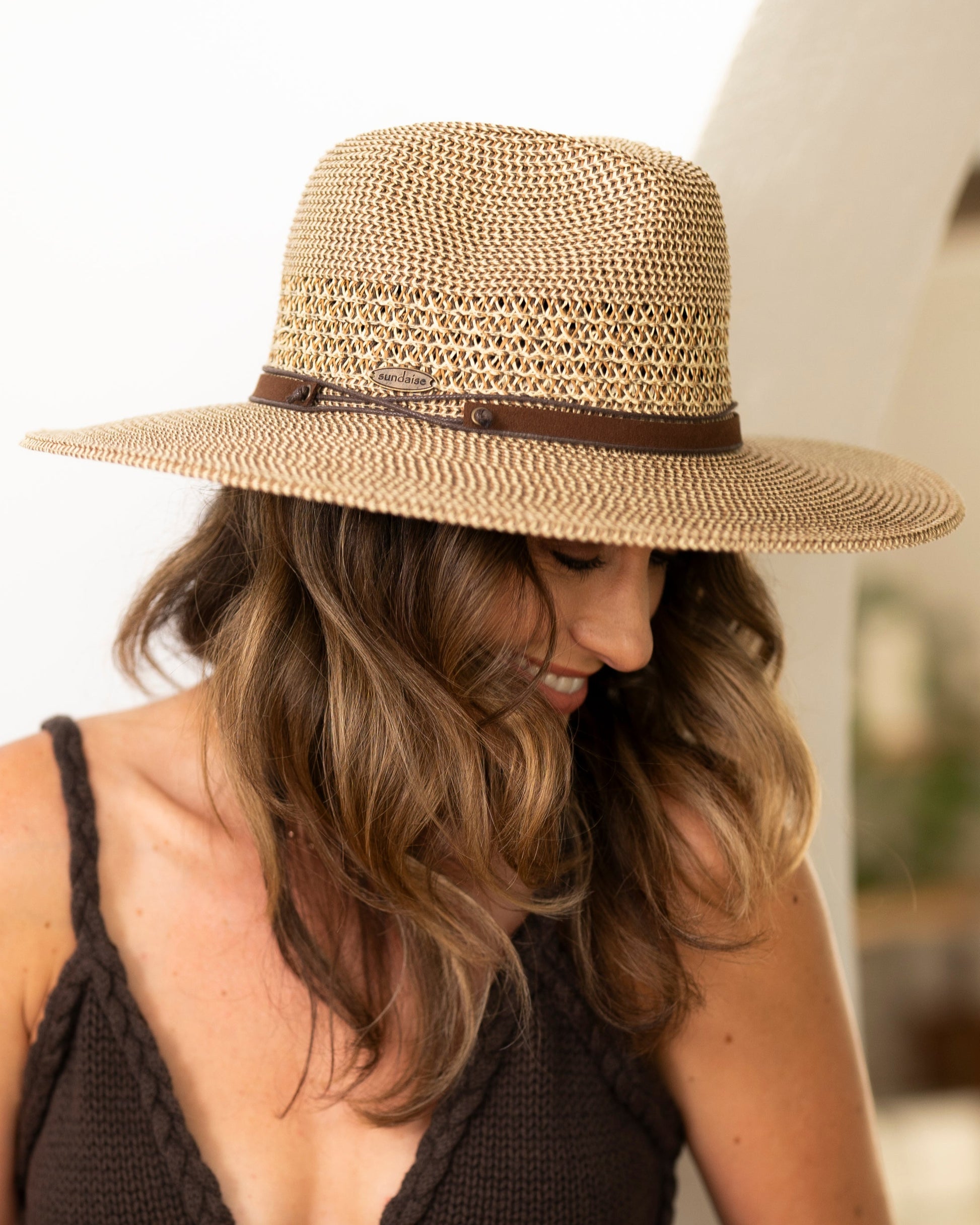 Woman wearing a black dress and straw hat indoors