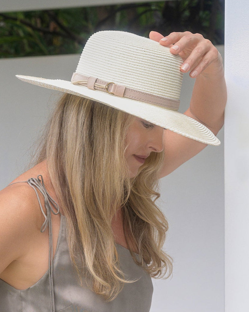 Woman wearing a white hat and gray outfit in an outdoor setting