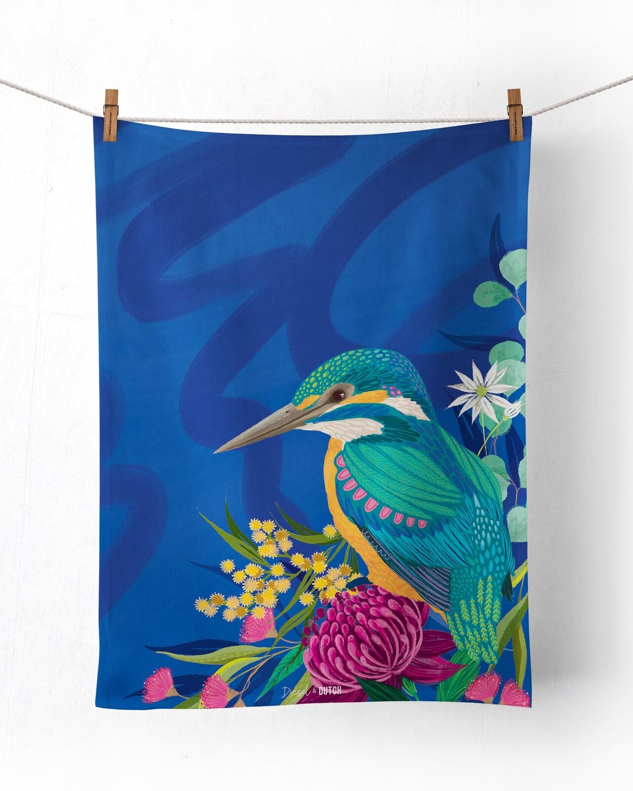 Decorative towel with a kingfisher design on a blue background, hanging on a line.