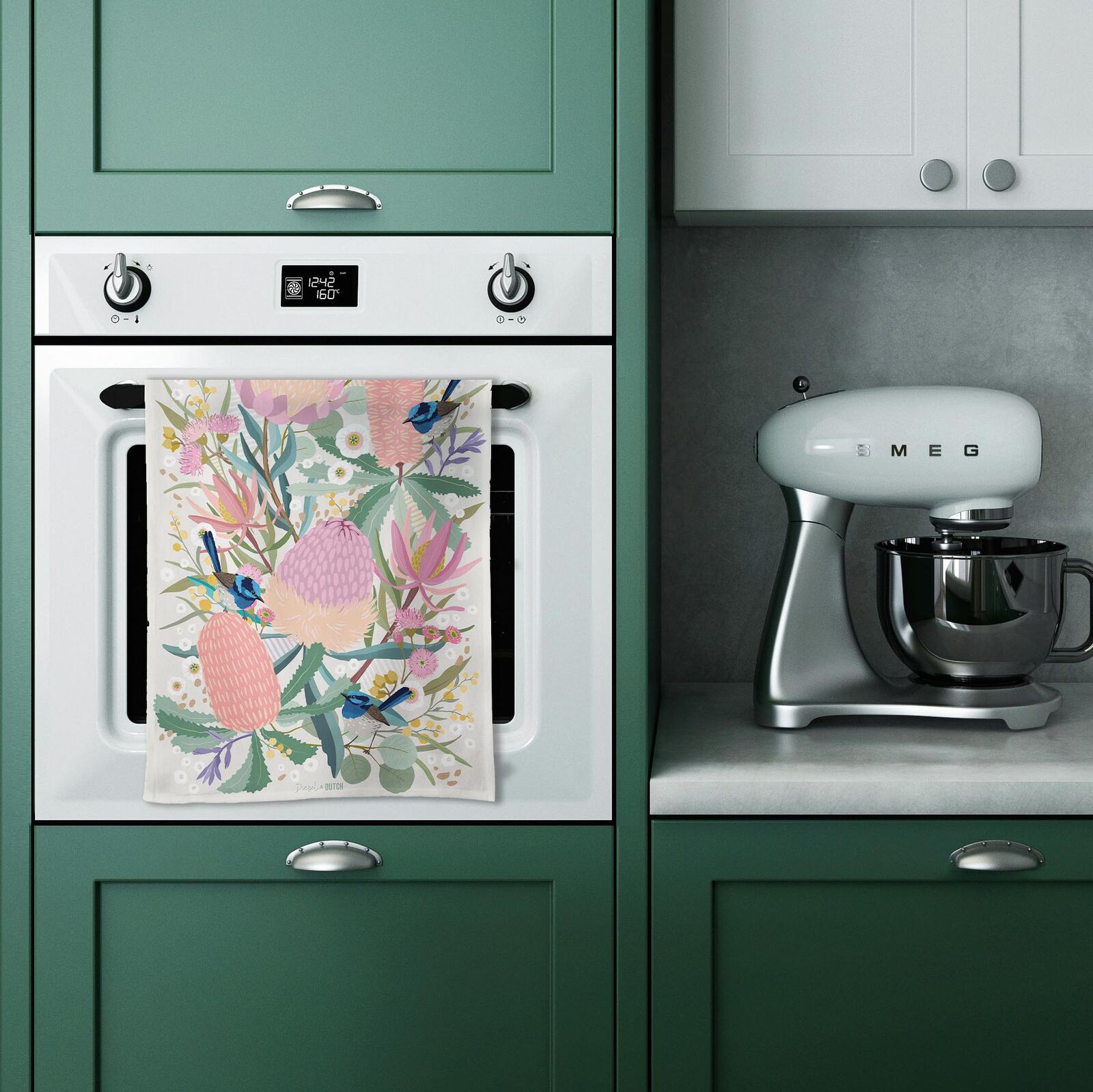 Kitchen with green cabinets, white oven, floral towel, and Smeg mixer.