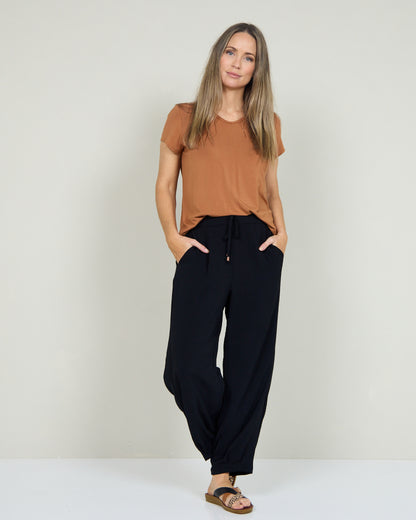 Venus Drawstring Tapered Pants in black, full-length view styled with a tan tee and sandals
