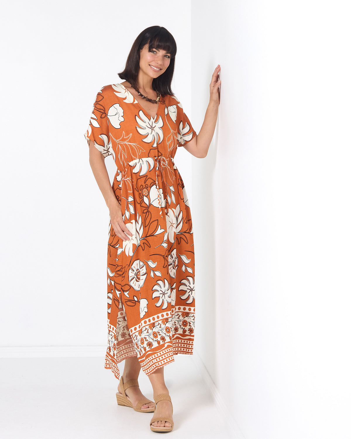 Montgomery Dress in toffee, three-quarter view leaning on a wall