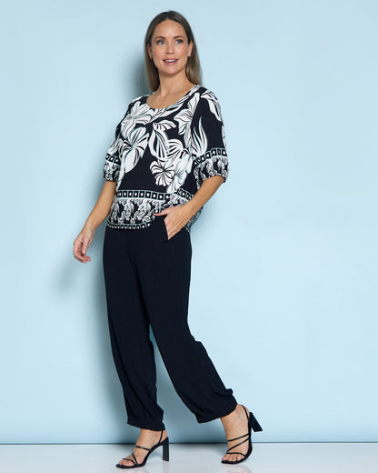 Falkiner Border Print Top in black, full-length view against a blue backdrop, worn with black pants
