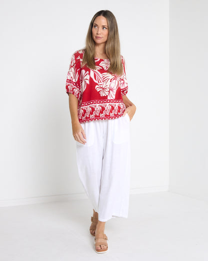 Falkiner Border Print Top in red, full-length view styled with white wide-leg pants