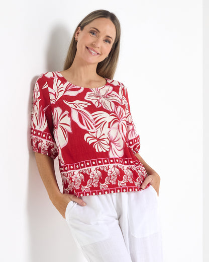 Falkiner Border Print Top in red, three-quarter view leaning on a wall